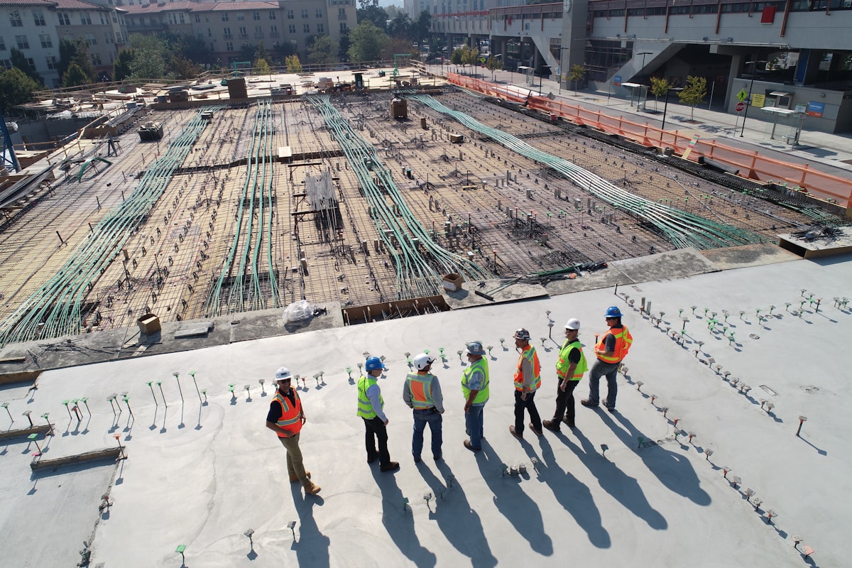 Aerial view of construction site with workers, rebar, and green conduit on concrete. — Vireo Homes