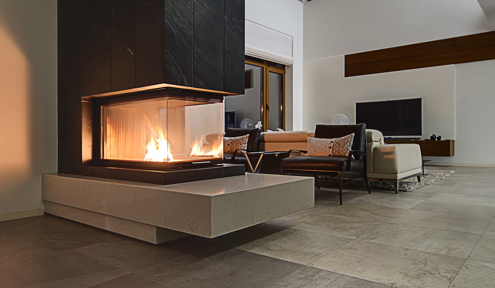 Modern living room with a black marble fireplace, glass firebox, and stylish dark leather — Vireo Homes